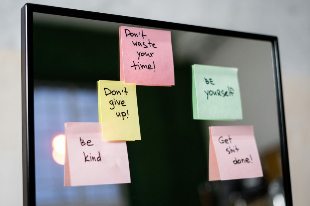 Colorful sticky notes with motivational messages on a mirror reflecting positivity.