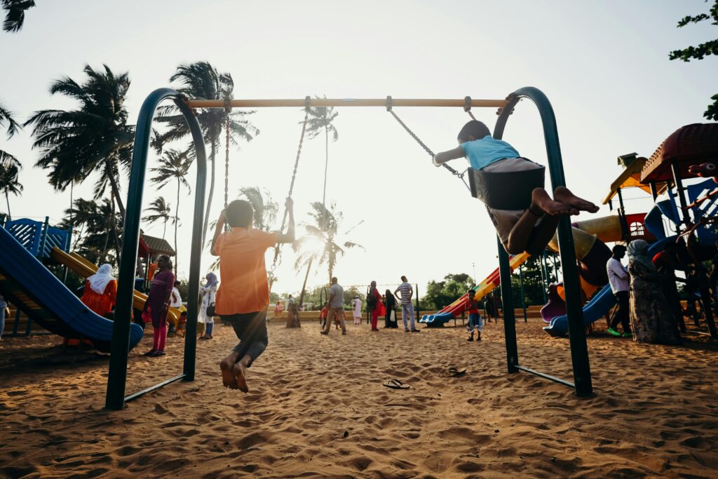 Kids swinging and enjoying a fun day at a tropical playground.