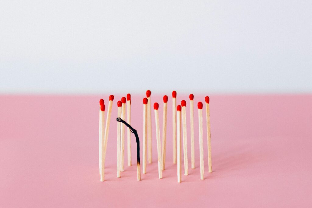 Artistic representation of burnout with matchsticks on a pink surface in a studio setting.